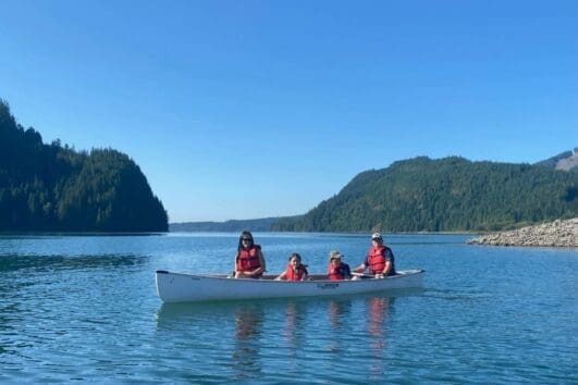 two kids are canoeing with their parents
